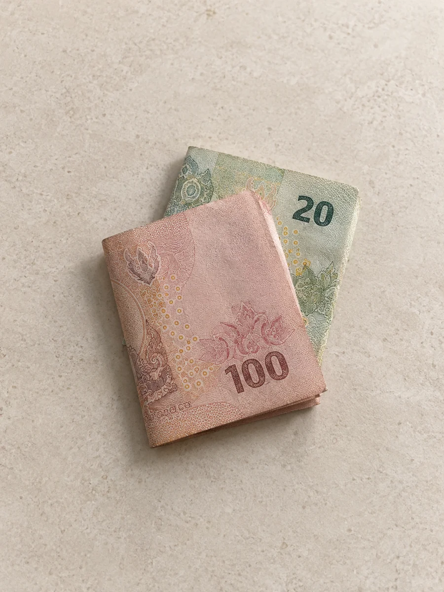 Dos billetes doblados sobre una superficie clara de piedra