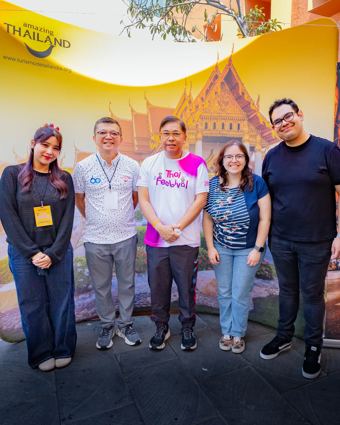 Paola y Andrew en una fotografía de grupo frente al fondo de Amazing Thailand en Thai Festival México 2026.